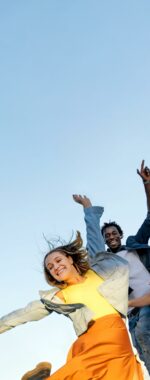 Group of young multiracial friends enjoying freedom together - Happy people jumping to blue sky background - Friendship concept